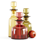 Three decorative glass bottles and red apple